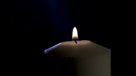 Slow-motion-macro-footage-of-a-white-candle-on-a-dark-background