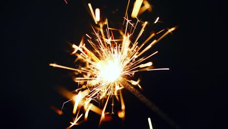 Close-up-burning-of-Christmas-sparkler.-Firework-lit-on-black-background.