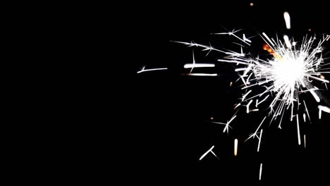 Close-up-burning-of-Christmas-sparkler.-Firework-lit-on-black-background.