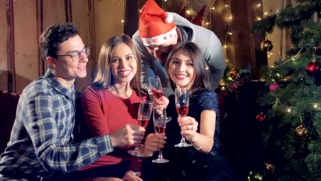 Portrait-of-4-cheerful-friends-at-new-year-christmas-party-looking-into-camera-holding-glasses-with-champagne.