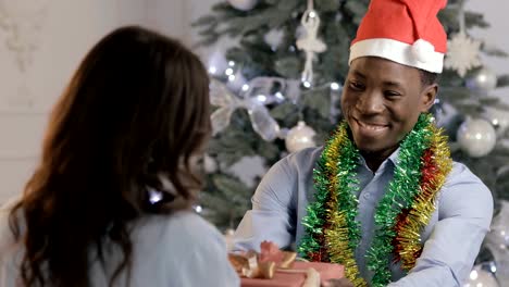 Man-in-Santa-hat-gives-a-gift-for-woman-on-Christmas-holiday