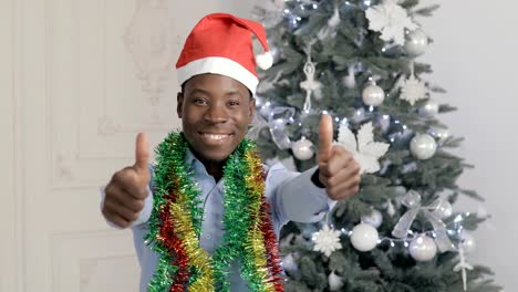 Okay-and-thumbs-up-gesture-of-african-man-in-Santa-Claus-hat,-Christmas-holiday