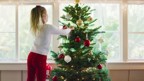 Junges-Mädchen-dekorieren-Weihnachtsbaum