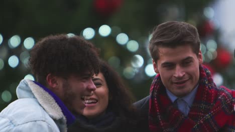 Friends-Stand-In-Front-Of-Christmas-Tree-On-South-Bank-In-London