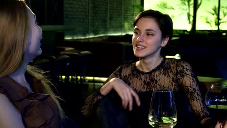 Two-beautiful-cheerful-girls-laughing-talking-at-the-bar-over-drinks