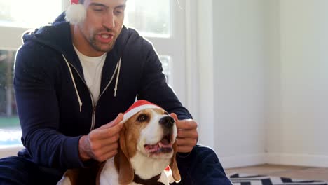 Sonriente-joven-poniendo-gorro-de-santa-en-su-mascota-perro-4K-4k