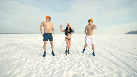 Drei-Freunde-tanzen-und-springen-während-der-kalten-Ausbildung-während-des-Tragens-Badeanzüge.-4K.