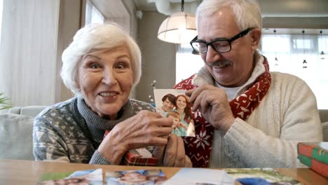 Senior-pareja-mostrando-la-foto-de-los-niños-en-la-mesa-de-restaurante