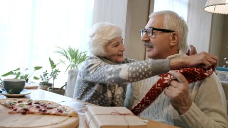 Ältere-Frau,-die-Man-an-Weihnachten-Abendessen-im-Cafe-Schal-anziehen