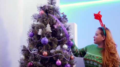 Girl-look-Christmas-tree-decoration-and-play-with-long-hair