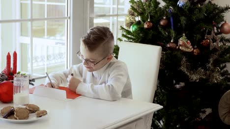 Happy-boy-writes-letter-to-Santa-and-eats-cookies