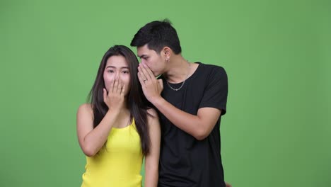 Young-Asian-couple-whispering-to-each-other