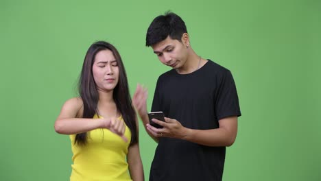 Young-Asian-couple-using-phone-and-getting-bad-news-together