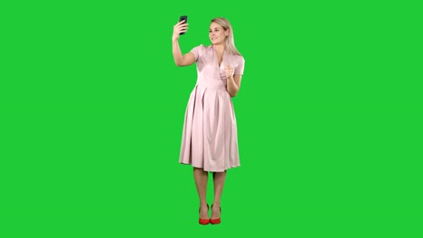 Mature-woman-wearing-light-pink-dress-making-selfie-on-a-Green-Screen,-Chroma-Key