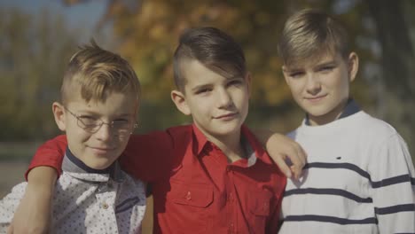 Three-young-boys-smiling-and-hugging-outdoors.-Brothers-spend-time-together.