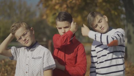 Three-boys-posing-at-the-camera-and-straightes-hair-outdoors.-Boys-spend-time-together.