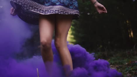 Beautiful-girl-in-a-dress-spins-around-in-purple-smoke-from-a-color-smoke-grenade,-slow-motion