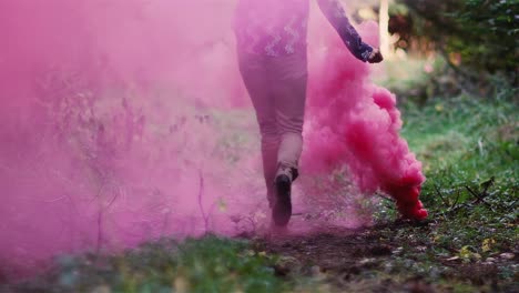 Hermosa-chica-en-un-bosque-corre-a-través-de-humo-rosa-de-una-Granada-de-humo-de-color,-cámara-lenta