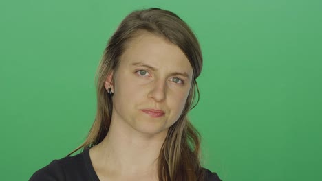 Young-women-looks-upset-and-shakes-her-head,-on-a-green-screen-studio-background