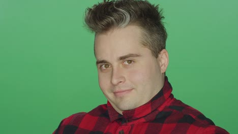 Young-man-winking-and-raising-his-eyebrows,-on-a-green-screen-studio-background