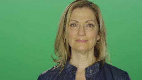 Beautiful-middle-aged-woman-starting-to-smile,-on-a-green-screen-studio-background