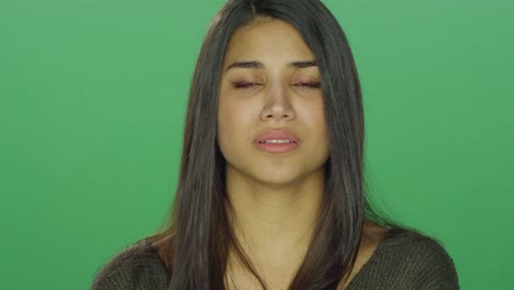 Young-woman-starting-to-recover-after-crying,-on-a-green-screen-studio-background