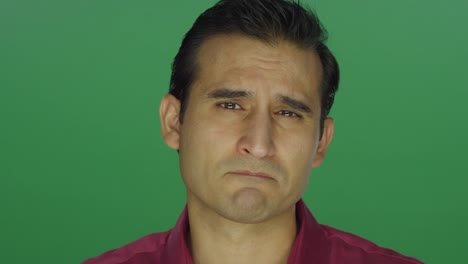 Ethnic-man-staring-worryingly-at-the-camera,-on-a-green-screen-studio-background