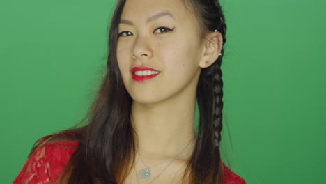 Young-Asian-woman-staring-and-looking-sexy,-on-a-green-screen-studio-background