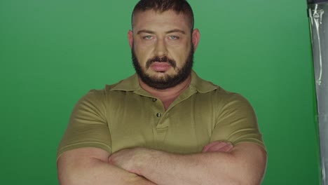 muscular-man-poses-with-his-arms-crossed,-on-a-green-screen-studio-background