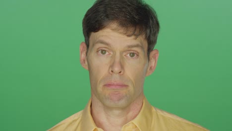 Middle-aged-man-looking-sad,-on-a-green-screen-studio-background