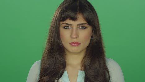 Tired-beautiful-brunette-woman-looking-slightly-concerned,-on-a-green-screen-studio-background