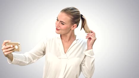 Businesswoman-taking-funny-selfie-with-phone-on-white-background