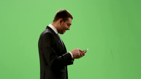 Geschäftsmann-im-Anzug-per-Smartphone-während-des-Gehens-auf-ein-Mock-up-green-Screen-im-Hintergrund.