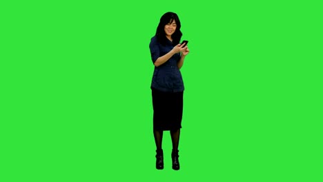 Beautiful-asian-girl-with-smartphone-singing-and-dancing-while-listening-to-music-on-a-Green-Screen,-Chroma-Key