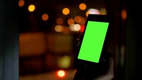 Woman-looking-at-smartphone-with-green-screen