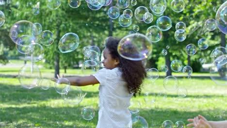 Kleine-Mädchen-und-jungen-fangen-Seifenblasen-beim-Spielen-im-freien