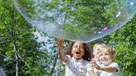 Begeistert-kleine-Kinder-tauchen-riesige-Seifenblase