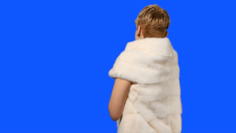 Beautiful-model-in-fur-cape-posing-for-camera-at-blue-background