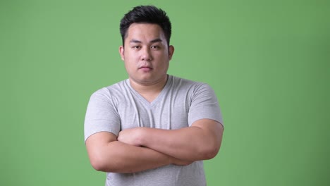 Young-handsome-overweight-Asian-man-against-green-background