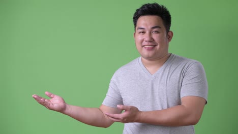 Young-handsome-overweight-Asian-man-against-green-background