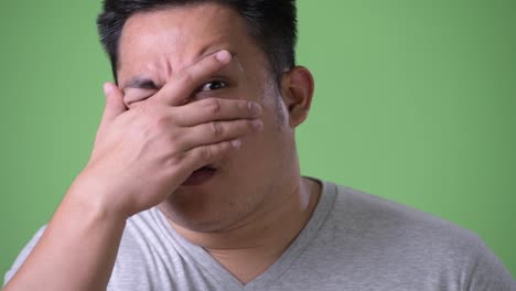 Young-handsome-overweight-Asian-man-against-green-background