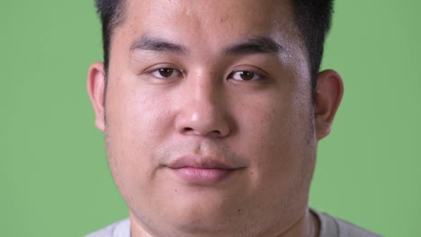 Young-handsome-overweight-Asian-man-against-green-background