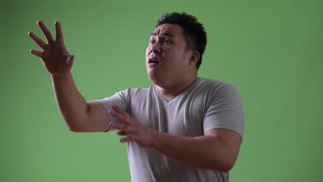 Young-handsome-overweight-Asian-man-against-green-background