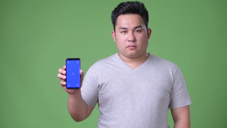 Young-handsome-overweight-Asian-man-against-green-background