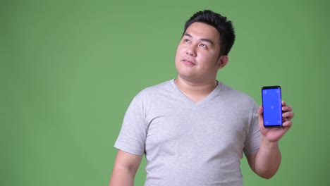 Young-handsome-overweight-Asian-man-against-green-background