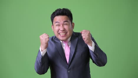 Young-handsome-overweight-Asian-businessman-against-green-background