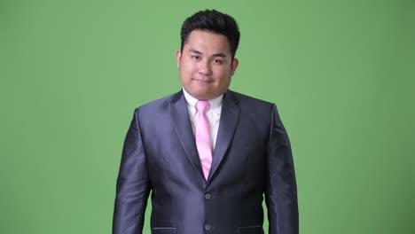 Young-handsome-overweight-Asian-businessman-against-green-background