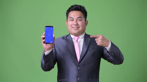 Young-handsome-overweight-Asian-businessman-against-green-background