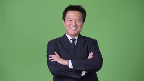 Mature-Japanese-businessman-against-green-background