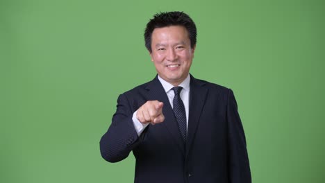 Mature-Japanese-businessman-against-green-background